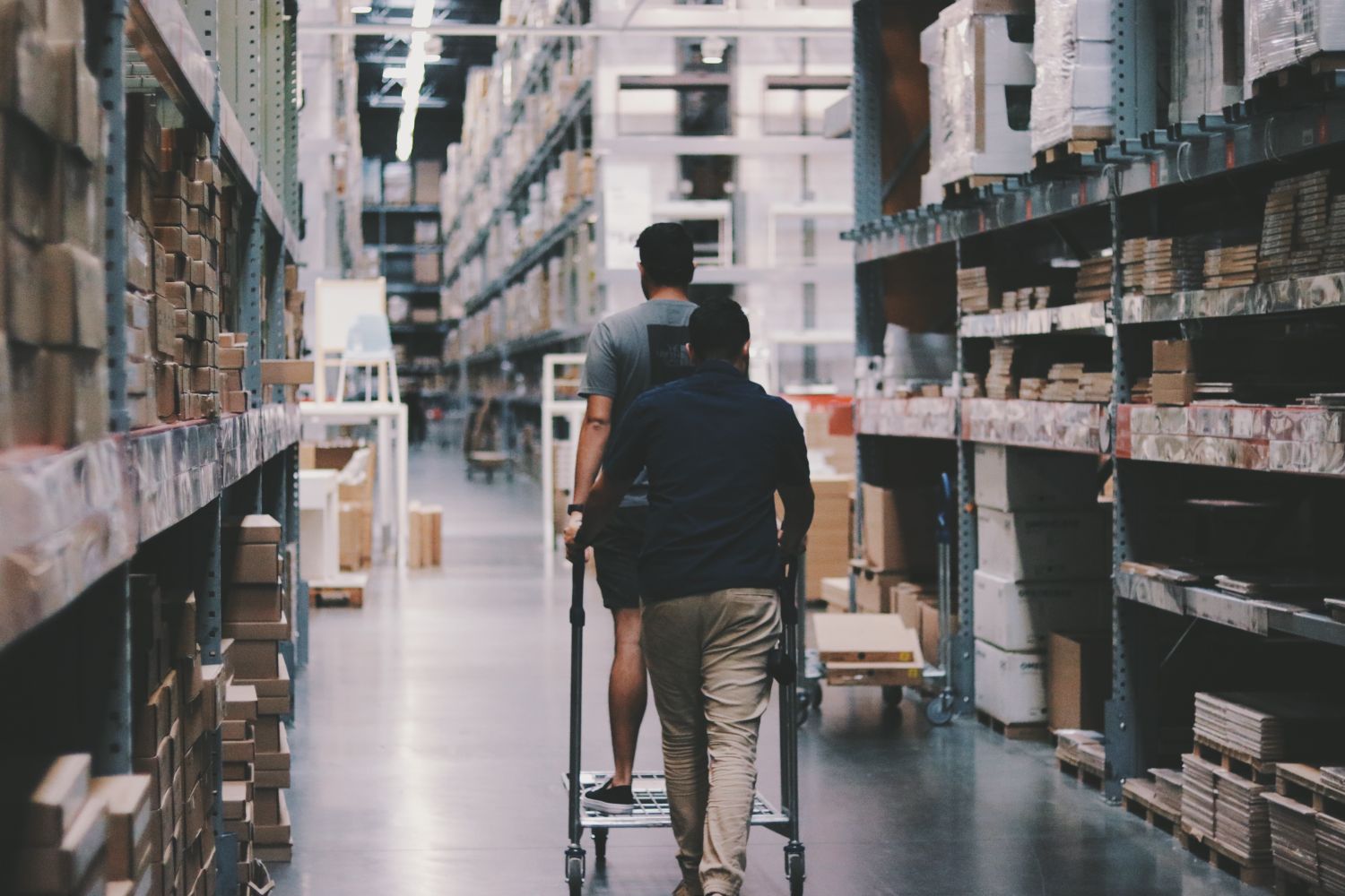 Workers in a warehouse aisle with tall racking